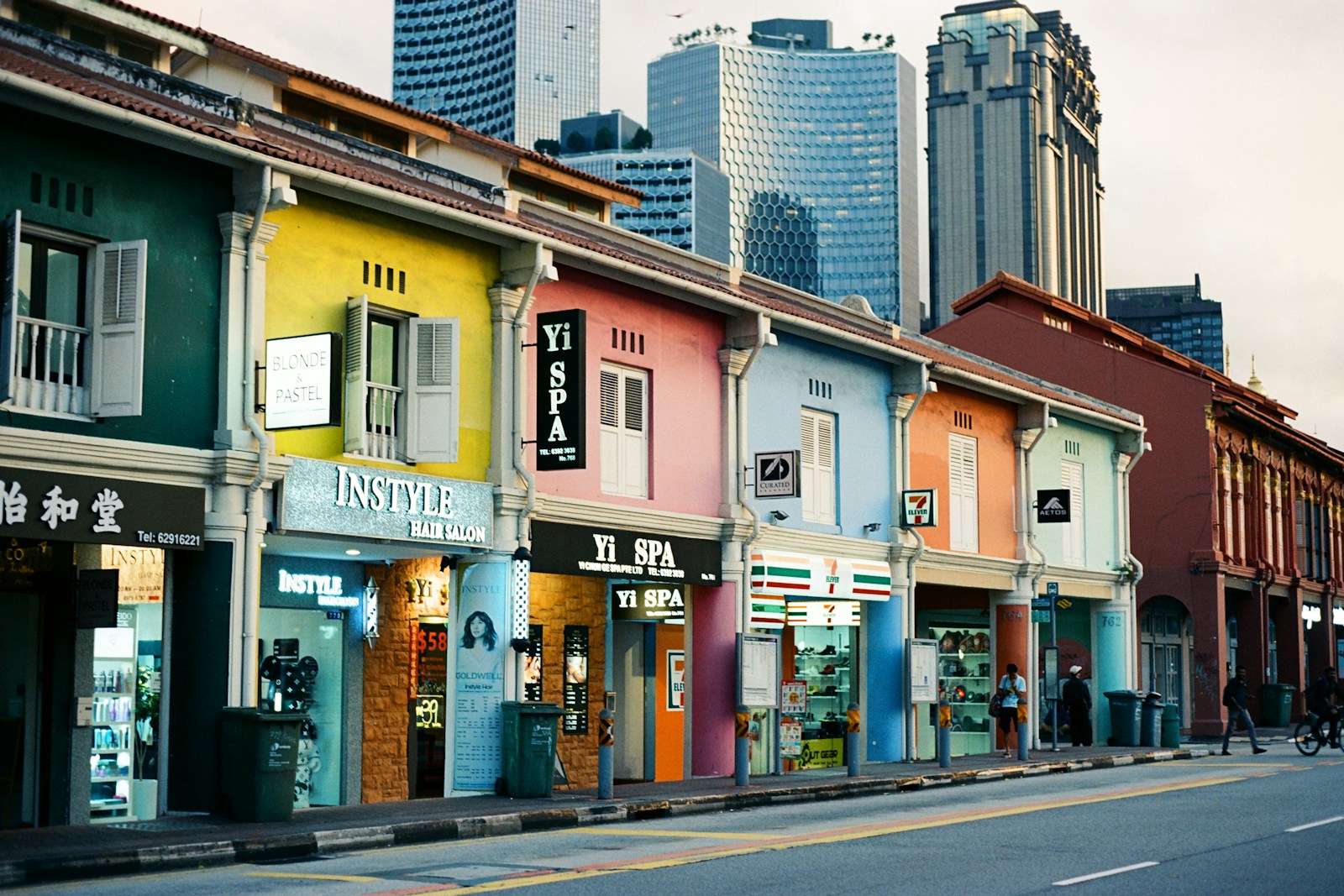 Colorful buildings line a street with skyscrapers.